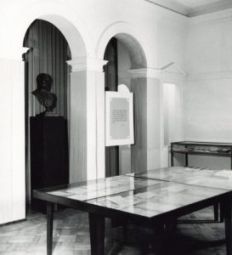 Sala II wystawy z 1958 roku poświęcona założycielom i założeniu Uniwersytetu, jego inauguracji i organizacji. Widać wnętrze obecnego magazynu bivlioteki Instytut Muzykologii. N a środku sali wielka gablota wyglądająca jak stół, a w niej, pod szkłem, mnóstwo dokumentów. Za gablotą przejście przez ścianę w kształcie dwóch łuków z filarem pośrodku, Przejście prowadzi do wnęki, w której stoi popiersie Stanisława Staszica.