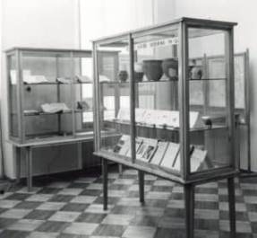 Na zdjęciu widać fragment wystawy z 1958 roku poświęconej historii Unwiersytetu Warszawskiego. Jest to części poświęcona archeologii polskiej i śródziemnomorskiej.Są tu dwie gabloty z dokumentami glinianymi naczyniami.